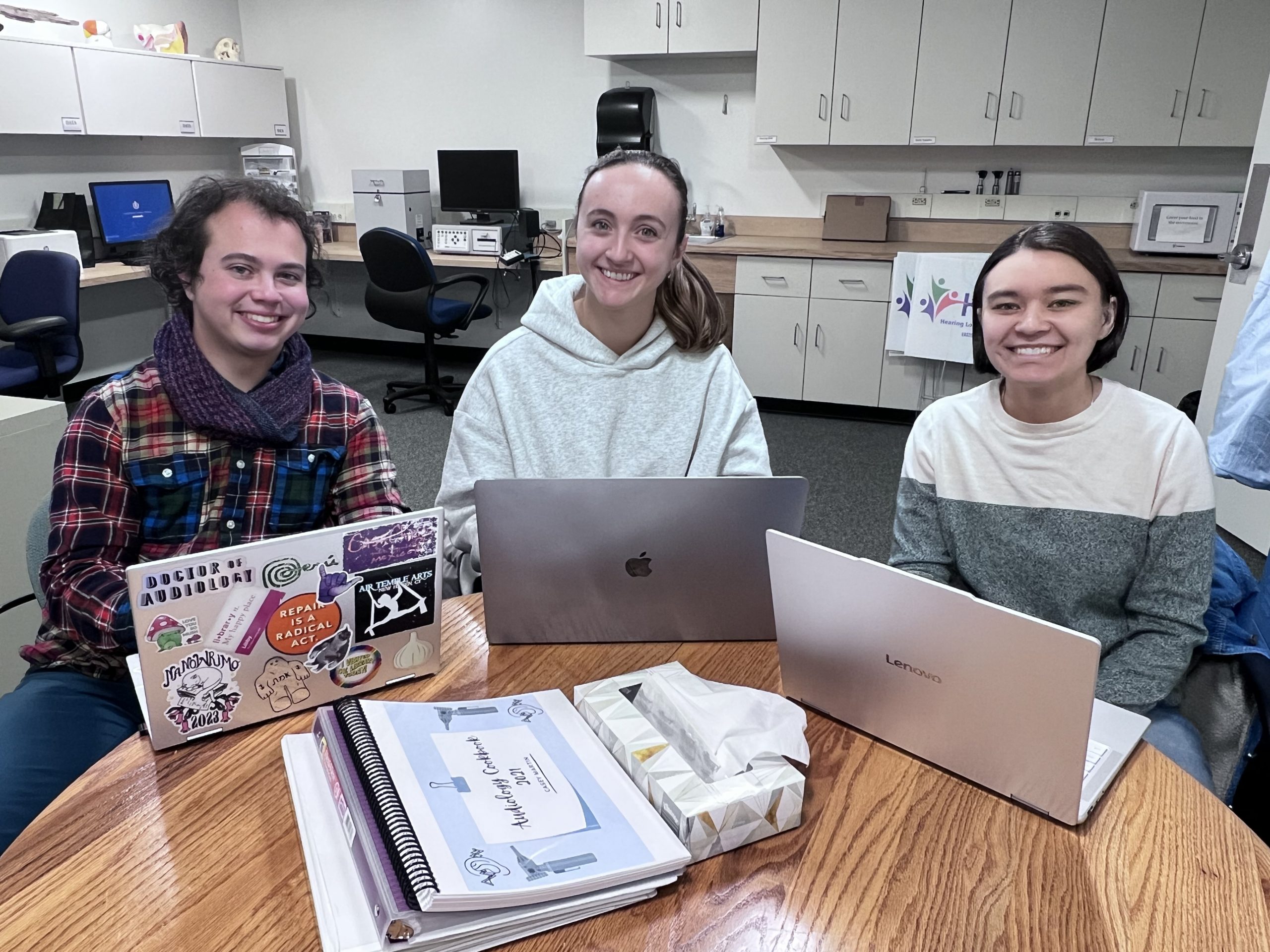2025 capstone group Three capstone student lab members sitting at a table in the AR lab with their laptops