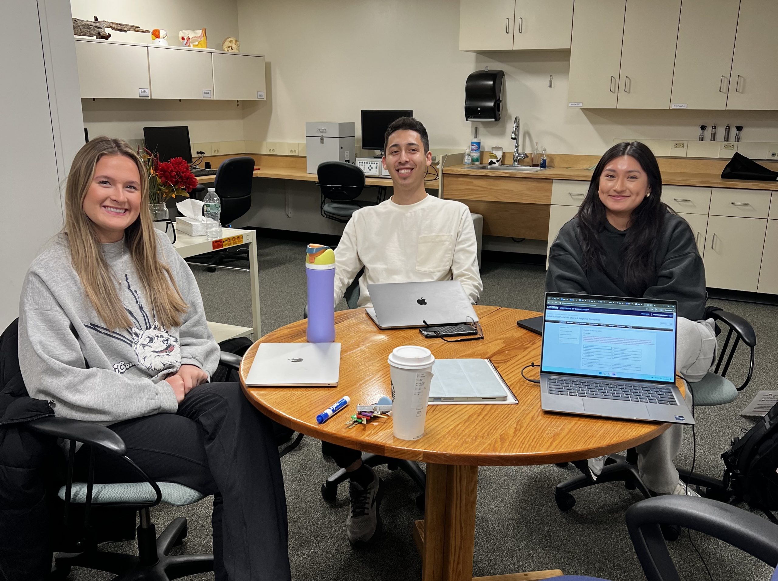 lab team1a Three student lab members sitting at a table in the AR lab with their laptops
